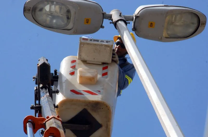 Funcionario da Prefeitura instala nova luminaria nos postes de Camburi