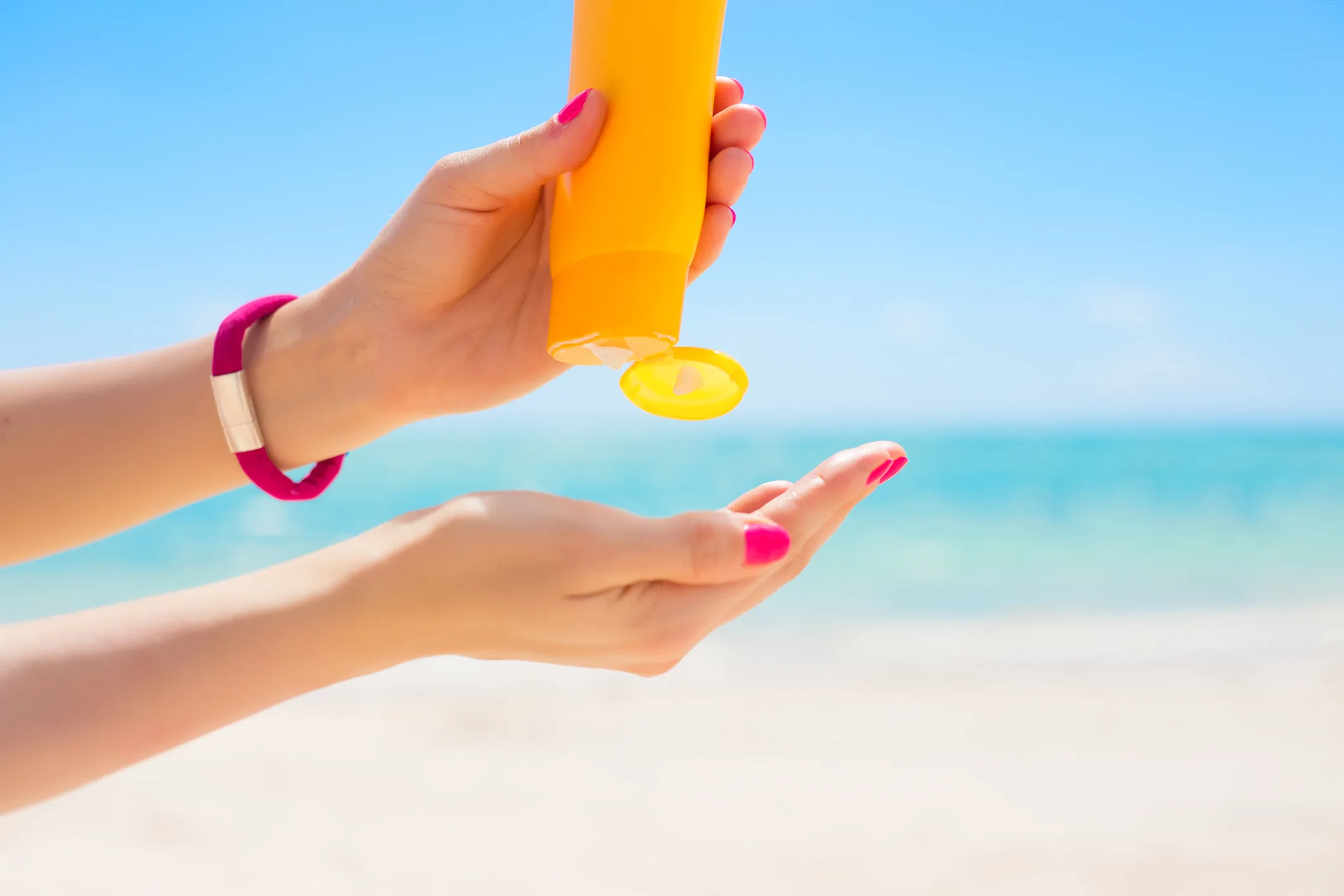 Woman using sunscreen cream in yellow bottle.