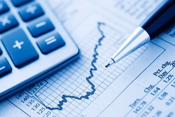 Close-up of a Calculator and Pen on a Financial Newspaper. Blue-toned.