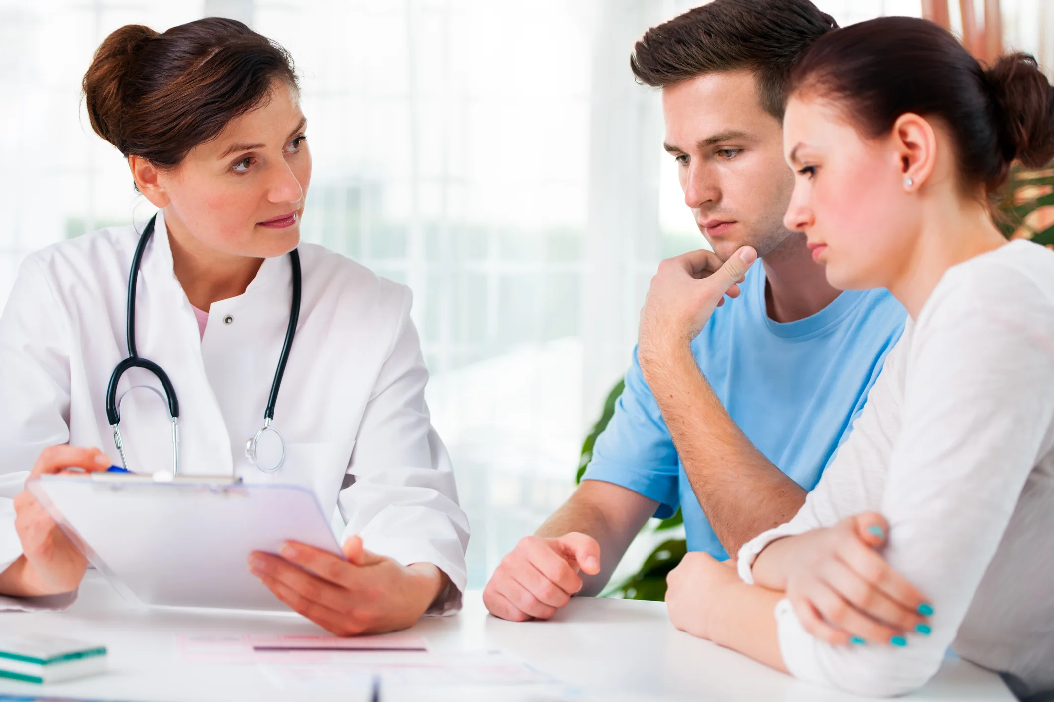 doctor woman offering medical advices to a young couple in office