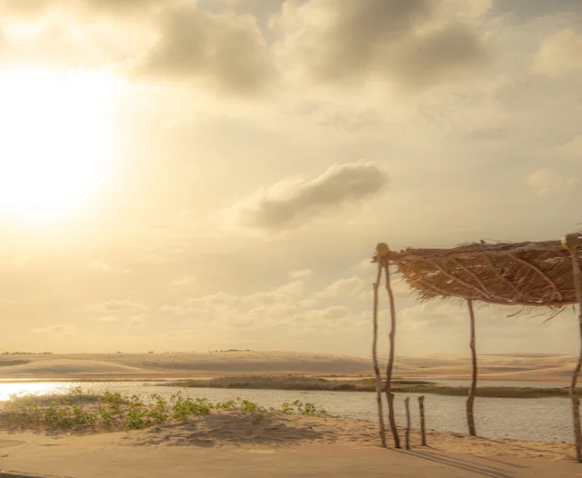 Paisagem em praia, com areia, sol e cabana