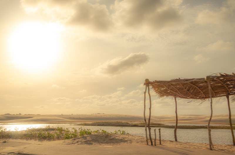 Paisagem em praia, com areia, sol e cabana