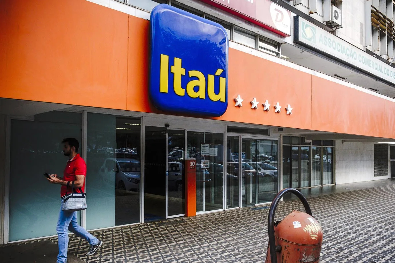 A pedestrian passes in front of a Itau Unibanco Holding SA bank branch in Brasilia, Brazil, on Friday, Jan. 20, 2017. Itau, the biggest bank in Latin America by market value, has reached an agreement to postpone to January 2022 the acquisition of shares of Colombia’s CorpBanca. Photographer: Gustavo Gomes/Bloomberg