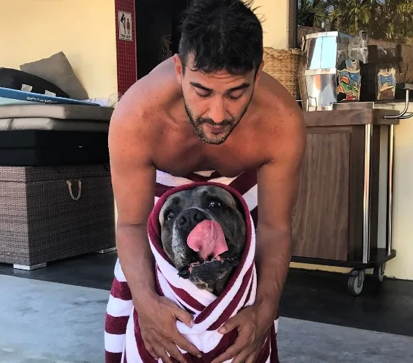 André Marques posa sem camisa cuidando de sua cachorra