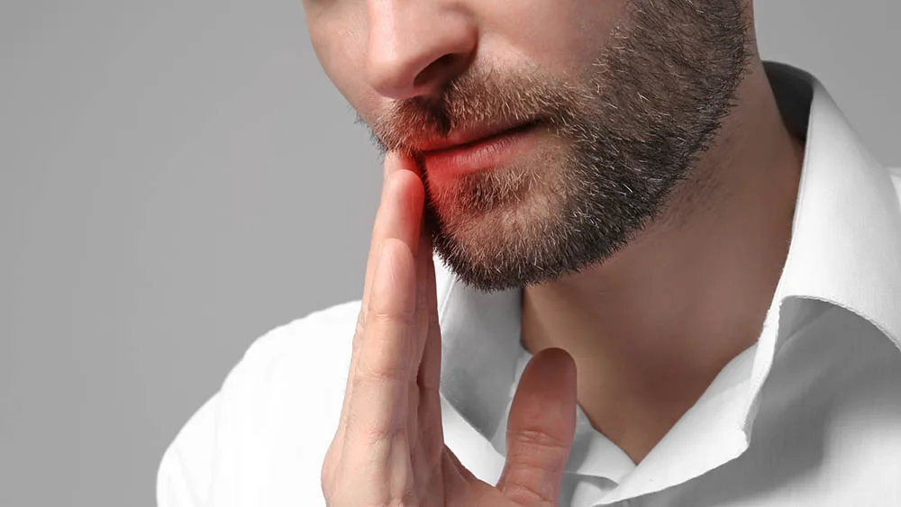 Man suffering from tooth pain on gray background. Health care concept