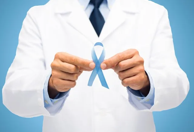 healthcare, profession, people and medicine concept – close up of male doctor hands holding sky blue prostate cancer awareness ribbon