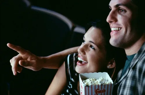 Close-up of a young couple watching a movie in a t