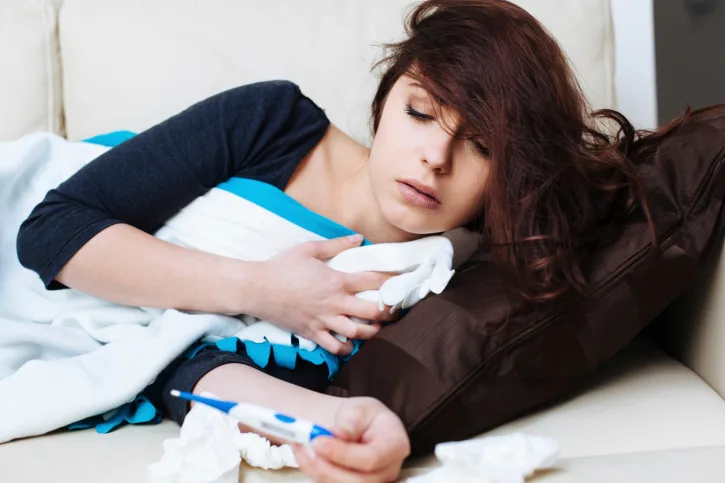 Sick woman lying with thermometer