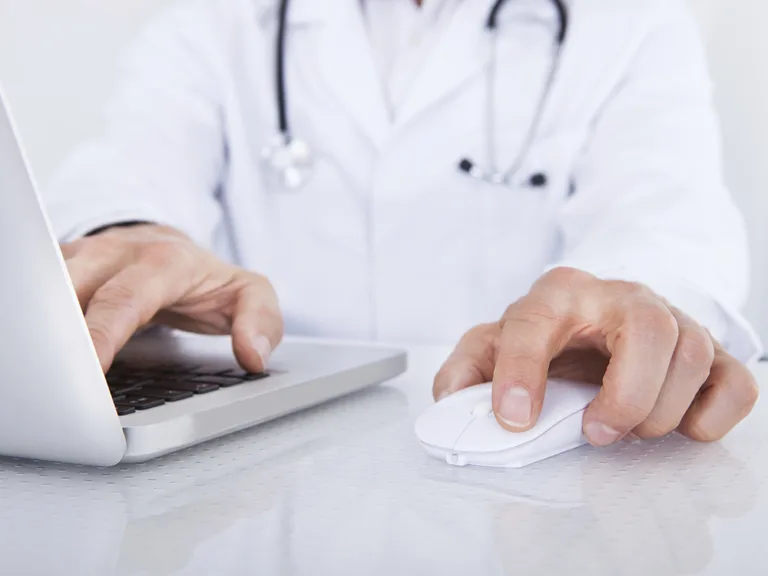 Close-up Of Doctor Using Laptop In Front Of Stethoscope At Desk