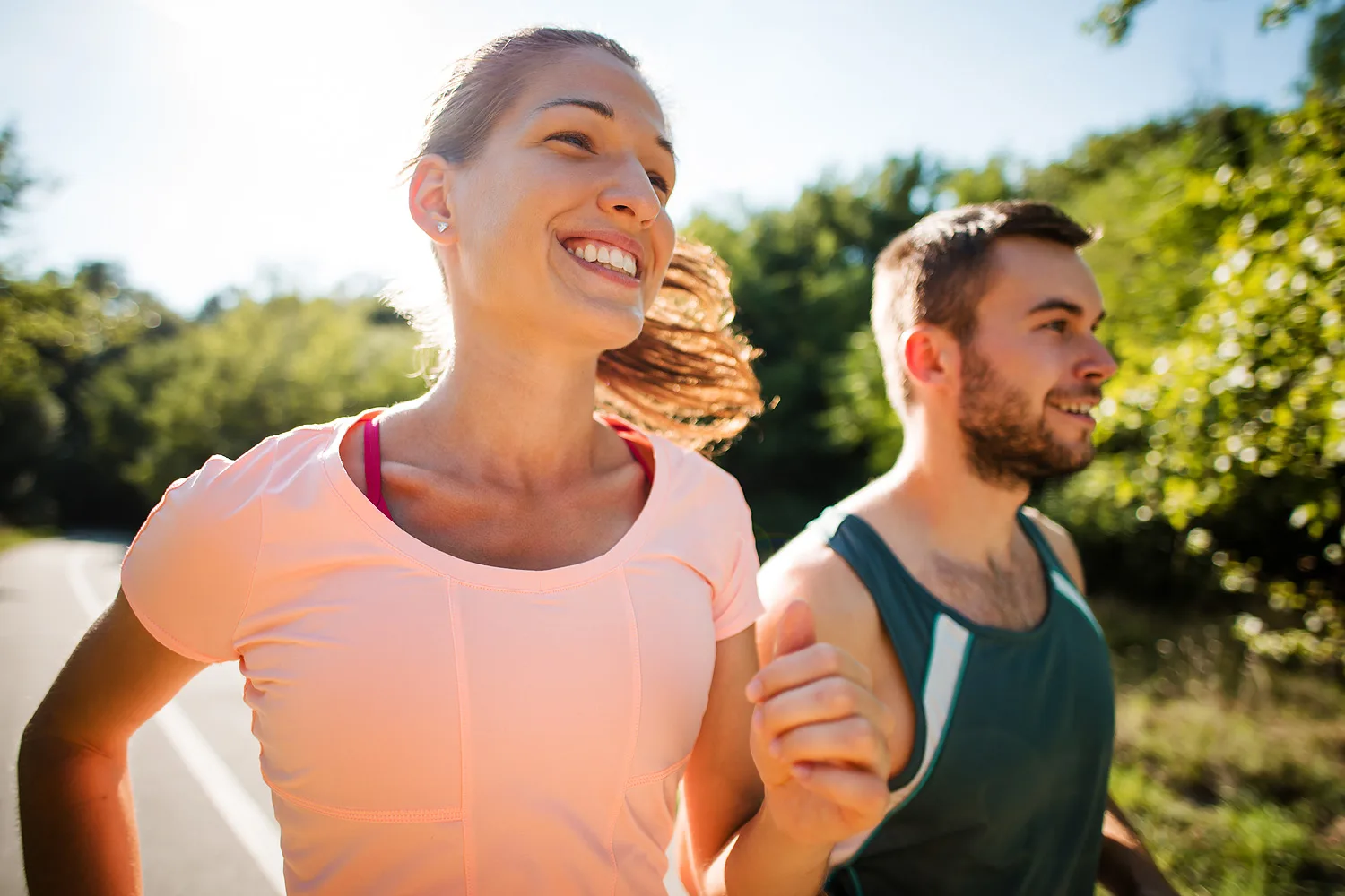 Closeup of smiling couple jogging together in summer sunny nature