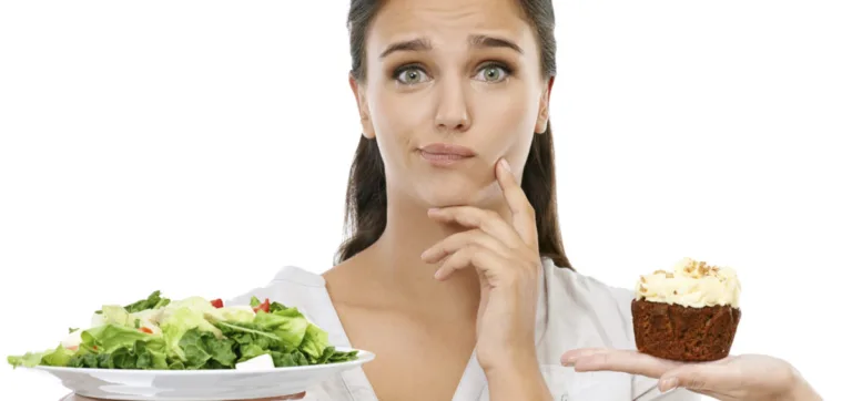 Studio shot of a young woman choosing between a healthy and unhealthy diet