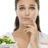 Studio shot of a young woman choosing between a healthy and unhealthy diet