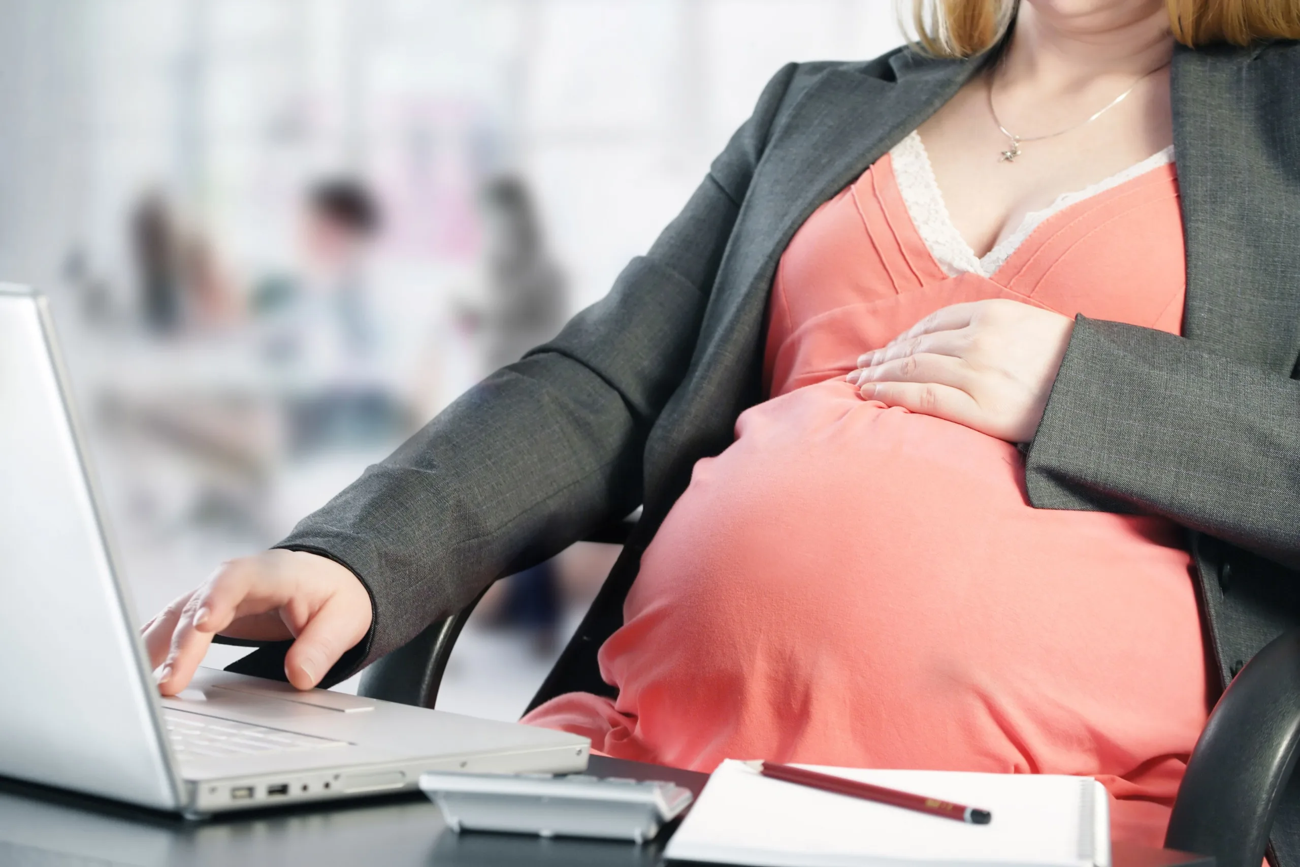 Working during pregnancy, woman sitting at her desk