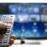 Television remote control changes channels thumb on the blue TV screen