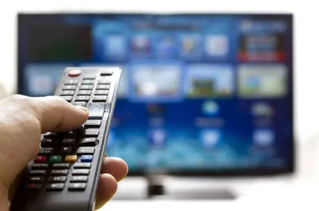 Television remote control changes channels thumb on the blue TV screen