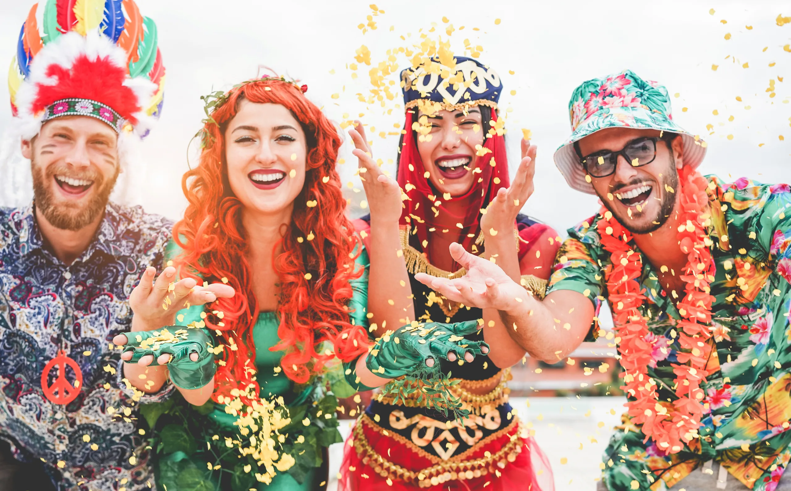 Happy dressed people celebrating at carnival party throwing confetti – Young friends having fun together at fest event – Youth, hangout, festive and happiness concept – Focus on left couple hands