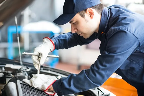 Portrait of an auto mechanic at work on a car in his garage