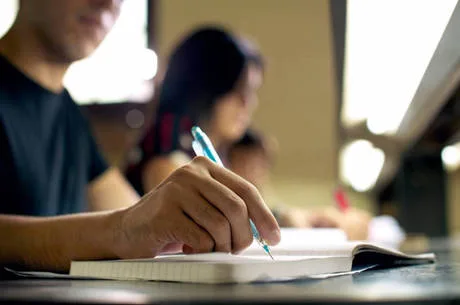 young man doing homework and studying in college library