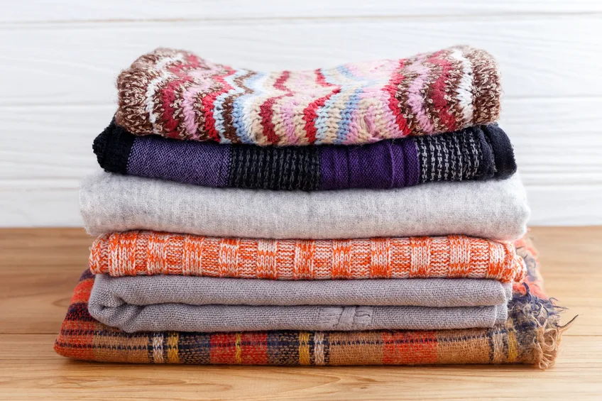 Winter fashion clothing stack with scarf gloves and blanket