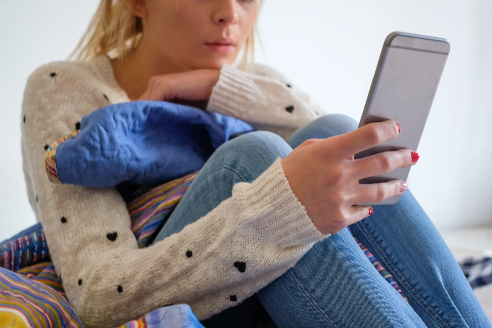 Girl using phone seated on the bed