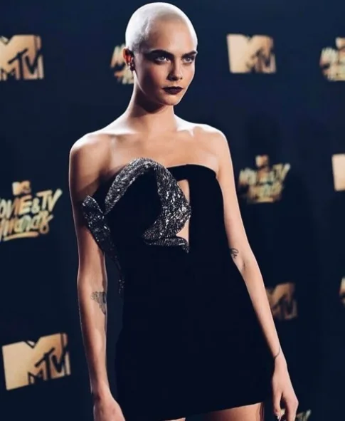 Após raspar cabelo para filme, Cara Delevingne usa peruca em set