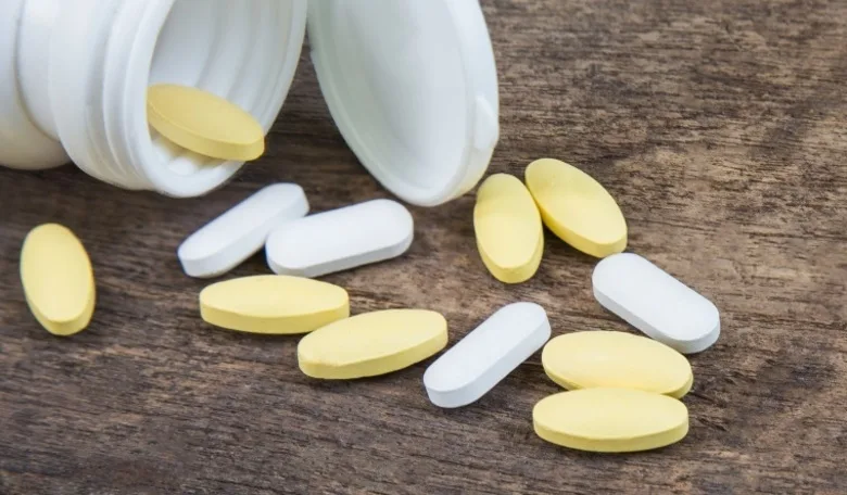 Pills spilling out of pill bottle on wooden background , medicine concept