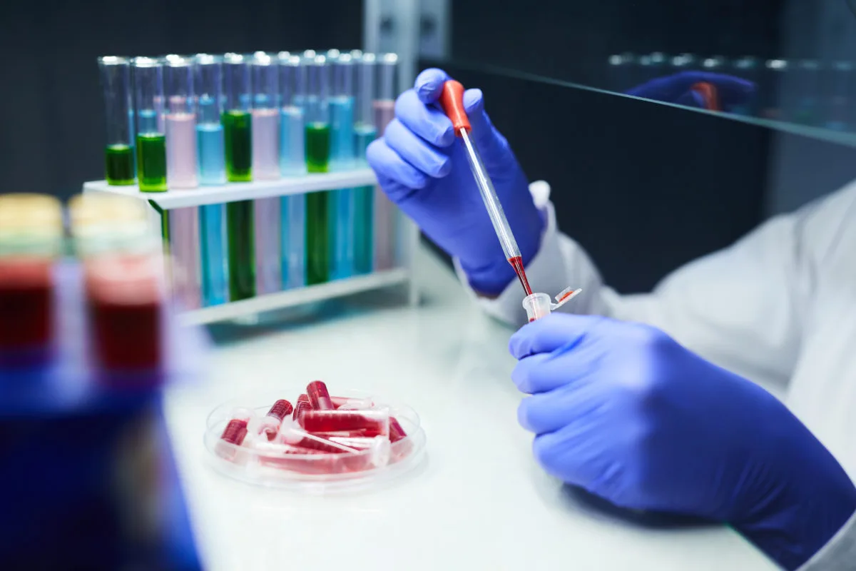 Close up of unrecognizable scientist dropping blood samples in test tubes while working on research in laboratory, copy space