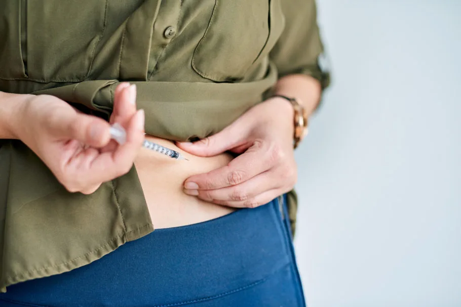 Closeup shot of an unidentifiable businesswoman injecting her stomach