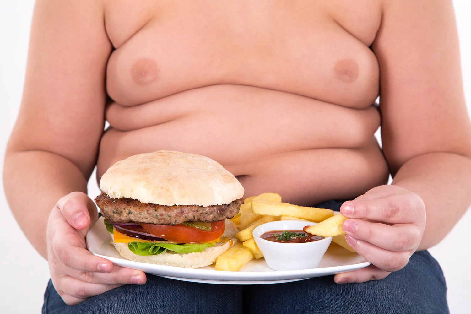 The boy eating a hamburger and french fries on white backround