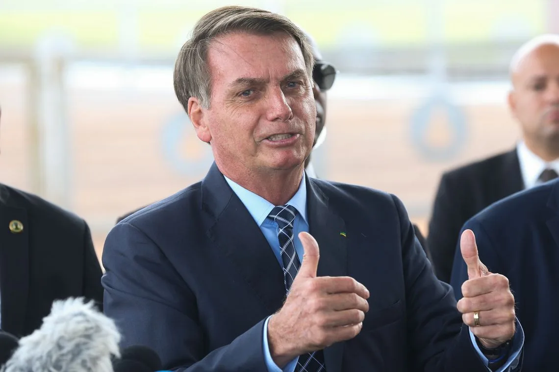 O presidente Jair Bolsonaro fala à imprensa e cumprimenta populares ao sair do Palácio da Alvorada