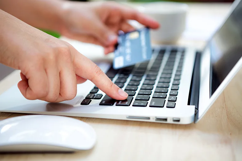 Hands holding a credit card and using laptop computer for online shopping