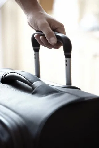 Hand holding travel suitcase in airport — Image by © Arman Zhenikeyev/Corbis