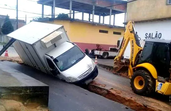 Caminhão baú cai dentro de buraco no meio da rua em Linhares