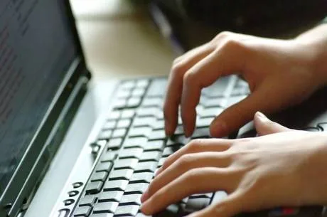 Hands typing on laptop keyboard.