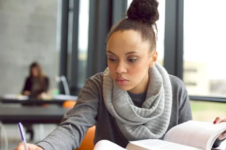 Young afro american woman doing assignments in library