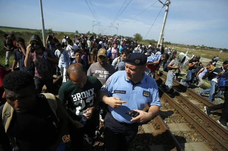 A Croatian policeman talks to a migrant as they walk on a railway track near Tovarnik, Croatia September 17, 2015. Croatian police said more than 5,000 migrants had arrived from Serbia since Hungary sealed its southern EU border with Serbia on Tuesday. REUTERS/Antonio Bronic