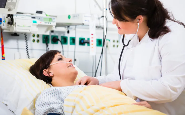 woman doctor at intensive care unit of clinic checking her patient with stethoscope