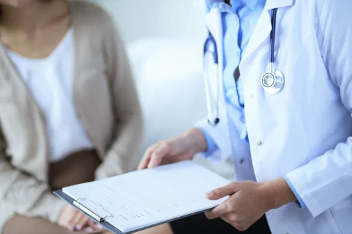 Female doctor holding application form while consulting patient