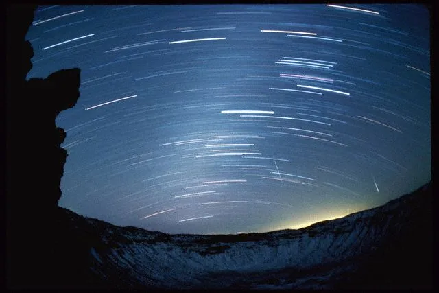 December 1985, Arizona, USA — Meteors from the Geminid meteor shower blaze across the night sky through the star trails at Arizona’s Meteor Crater. — Image by © Jonathan Blair/Corbis