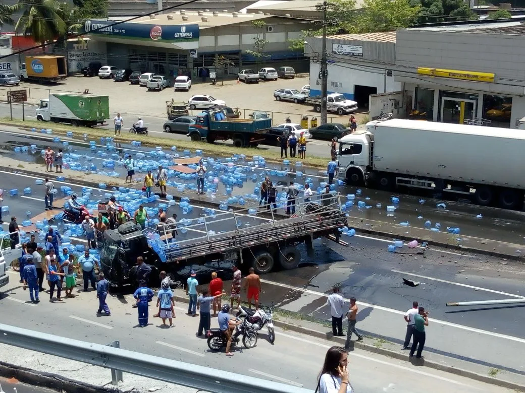 Caminhão com galões de água se envolve em acidente e carga se espalha na pista em Viana