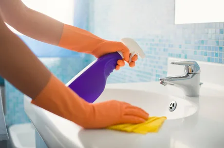 woman doing chores cleaning bathroom at home