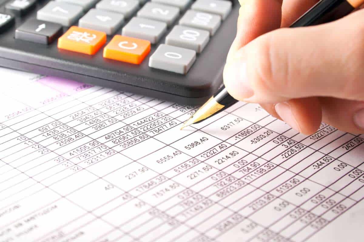 Close up of a calculator, spreadsheet, data and pen on a table.