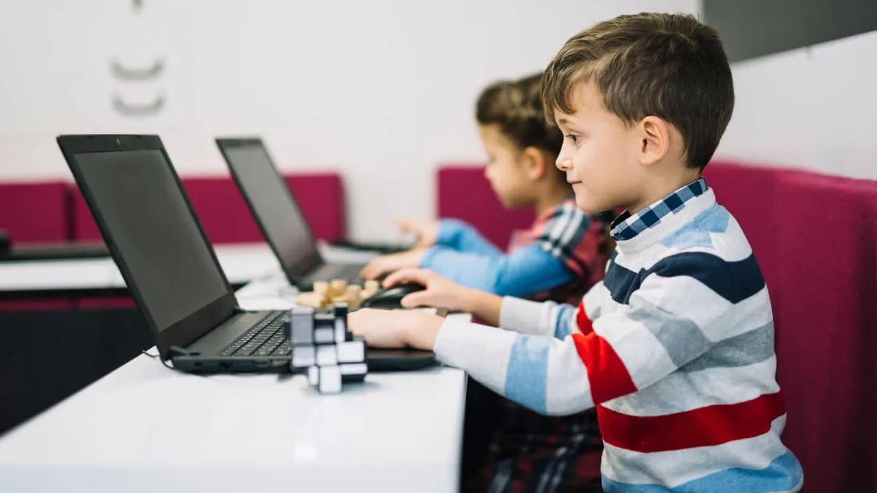 Crianças usam computador em sala de aula