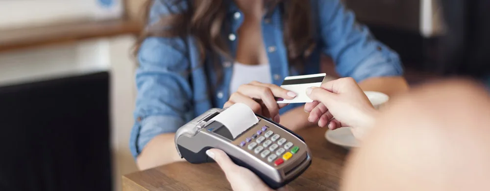 Smiling woman paying for coffee by credit card