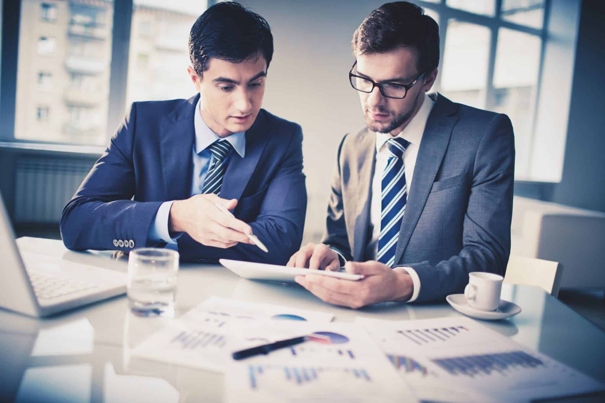 Image of two young businessmen discussing new project in office