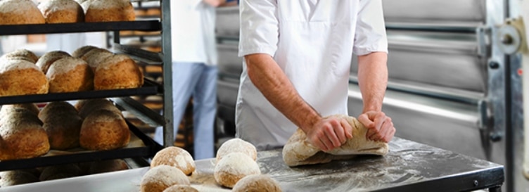 Baker kneading bread dough in bakery