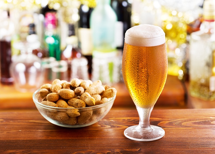 glass of beer with peanuts in a bar