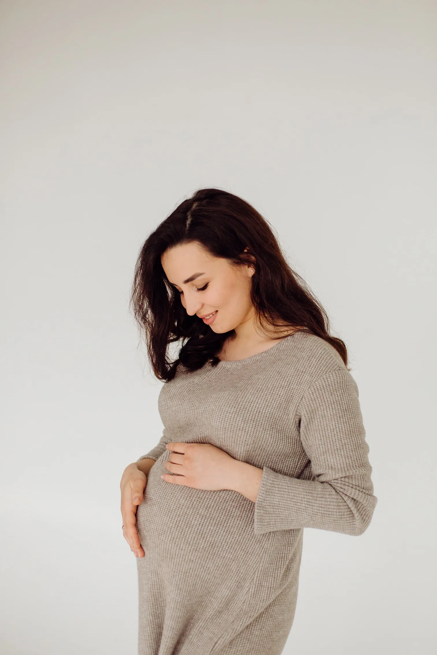 Beautiful young pregnant woman posing in studio in dress