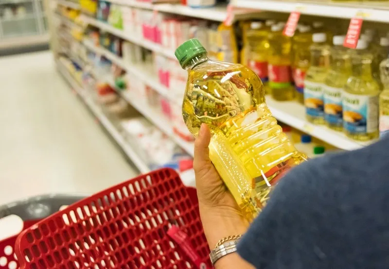 Caucasian housewife shopping for vegetable oil in a supermarket alley