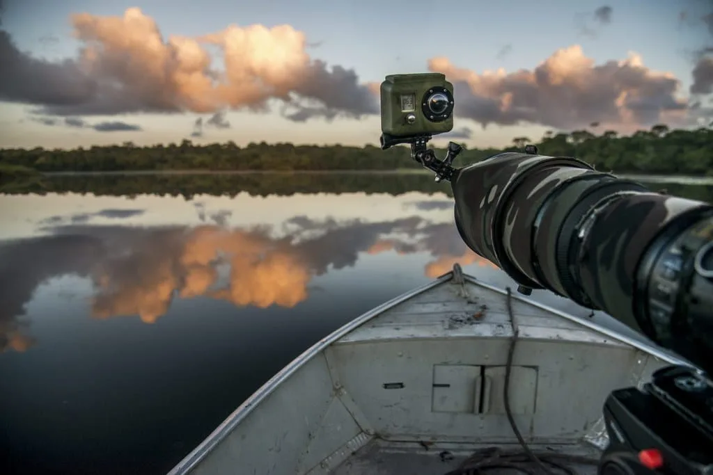 Lago durante a 'hora mágica' com uma lente teleobjetiva pronta para capturar a rápida mudança de luz.Finalidade da Imagem: A imagem destaca a beleza da luz natural durante a hora mágica e a necessidade de adaptação rápida do equipamento fotográfico para capturar esses momentos.